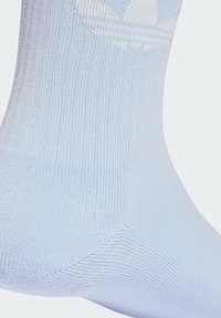 Jasnoniebieska skarpetka sportowa wykonana z gładkiego, prążkowanego materiału. Posiada białe logo na górze oraz wzmocnioną piętę, z bezszwową konstrukcją.
