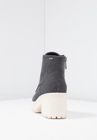 Stivaletto in tessuto grigio con suola platform bianca e dettagli con zip laterale. Presenta una punta rotonda e una finitura in tessuto strutturato.