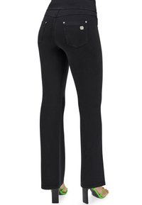 Mustat farkut, joissa on tiukka malli, suorat lahkeet ja takataskut. Korostettu hopeisilla yksityiskohdilla ja yhdistetty vihreisiin korkokenkiin.