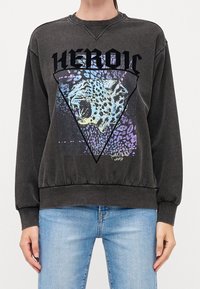 Tummanharmaa huppari, jonka etuosassa on leopardikuvio kolmiossa, musta teksti "HEROIN" sekä elastiset hihansuut ja helma.