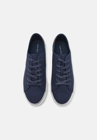 Marineblaue Leinenschuhe mit weißen Gummisohlen, abgerundeter Spitze und strukturiertem Obermaterial. Sie verfügen über Band-Schnürsenkel und ein dezentes Markenlogo.