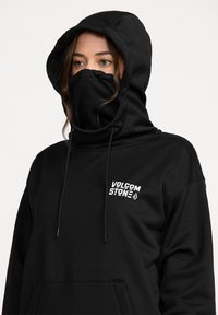 Sweatshirt à capuche noire avec poche avant, cordons de serrage ajustables et logo imprimé sur la poitrine. Le tissu semble lisse et robuste.