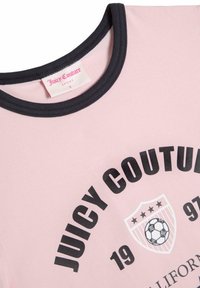 Růžové tričko s krátkým rukávem a černým kulatým textem "JUICY COUTURE", s grafikou fotbalového míče a námořnickým obvodem u krku. Viditelná značka.