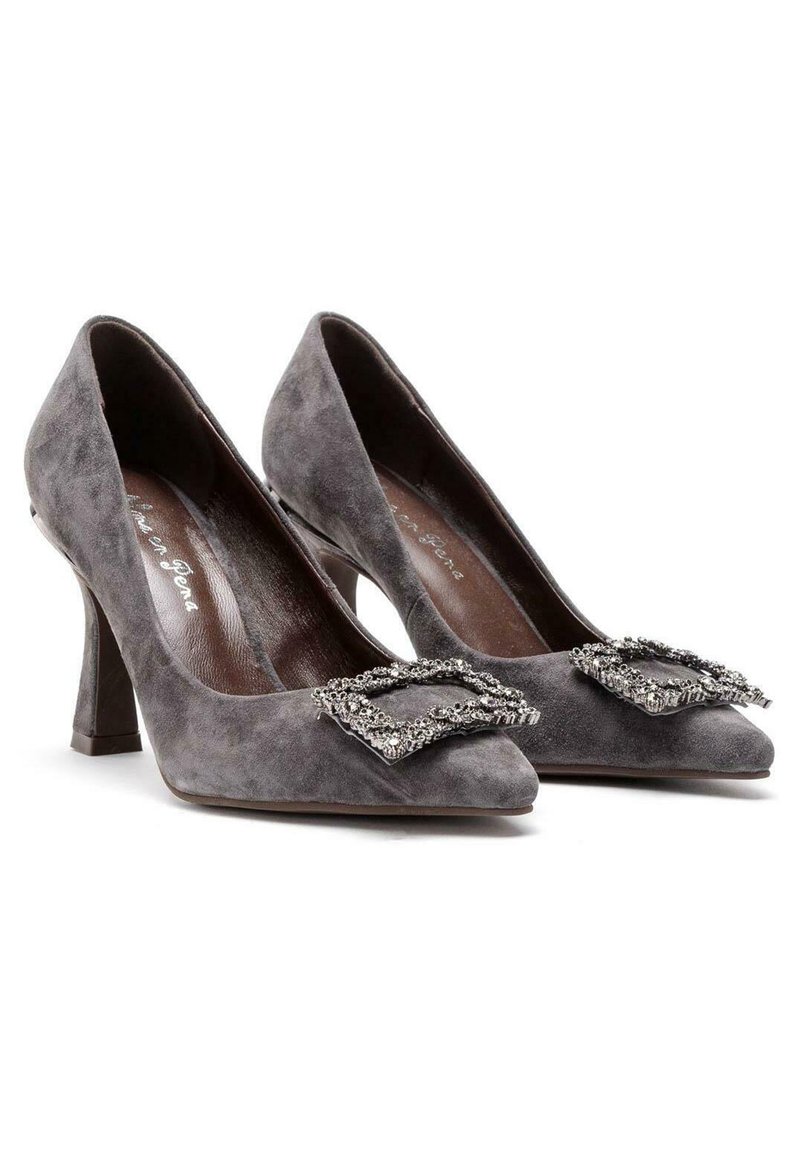 Tacones altos de ante gris con puntera afilada y una hebilla decorativa con acentos de strass en el empeine. Con una altura de tacón moderada.