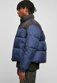 Padded jacket so zaujímavým modro vzorovaným spodným polom, čiernym horným dielom, vysokým golierom a elastickými manžetami.