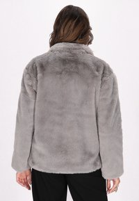 Jachetă din blană sintetică gri, cu o textură moale, gulere mai lat și mâneci lungi. Design simplu, cu un tiv ușor rotunjit în spate.