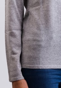 Maglione grigio in morbida lana, con maniche lunghe e scollo rotondo. Il tessuto è lavorato a maglia con una consistenza liscia.