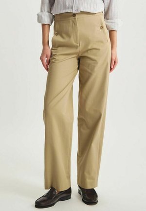 Pantalons beiges sur mesure en tissu lisse, dotés d'une taille haute et de deux boutons à l'avant, avec une coupe décontractée et des jambes droites.