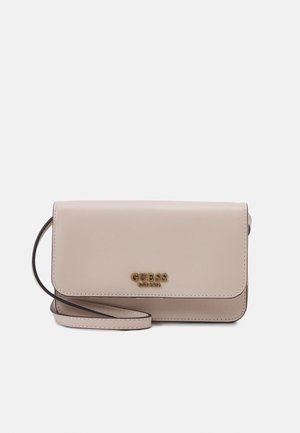 Beige syntetisk håndtaske med klaplukning, prægede guldlogo foran og en tynd sort skulderrem. Glat tekstur, minimalistisk design.