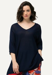 Navyblaues, locker gestricktes V-Ausschnitt-Oberteil mit 3/4-Ärmeln, das eine entspannte Passform und eine weiche Textur bietet. Ausgezeichnet durch Einfachheit und Vielseitigkeit.