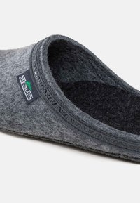Grijze gevoerde pantoffel met een zachte binnenvoering, ronde vorm en decoratieve stiksels langs deopening. Beschikt over een klein merklabel dat is gestikt.