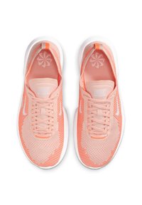 Nike'i kergedad kergest võrgu pealmise osaga pastellroosas, valgete aktsentidega ja tekstureeritud tallaga, millel on paeltega esiosa ja logo detail.