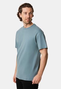 Kortärmad t-shirt i ljusblått, tillverkad av en mjuk bomullsblandning, med rundad halsringning och avslappnad passform med sömnadsdetaljer längs sömmarna.