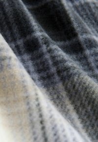 Villane kangas, tekstuuriga halli ja kreemika segu. Sisaldab peent mustrit erinevates toonides ning on pehme ja karvane.