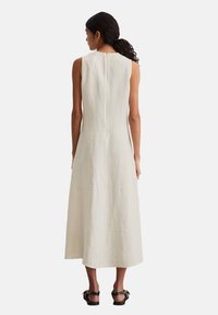 Ärmelloses, mittellanges Kleid aus hellem beigen Leinen. Verfügt über einen dezenten Reißverschluss im Rücken und ein tailliertes Oberteil, das zum Saum hin ausgestellt ist.