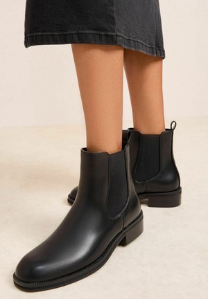 Schwarze Lederstiefeletten mit elastischen Seitenpaneelen, runder Zehenpartie und flachem Absatz; glatte Oberfläche mit kontrastierenden Nähten.