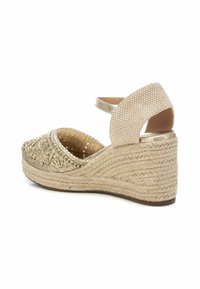 Sandali con zeppa beige con tacco in corda intrecciata texturizzata. Design ricamato sulla parte superiore e una fascia dorata per una vestibilità sicura.