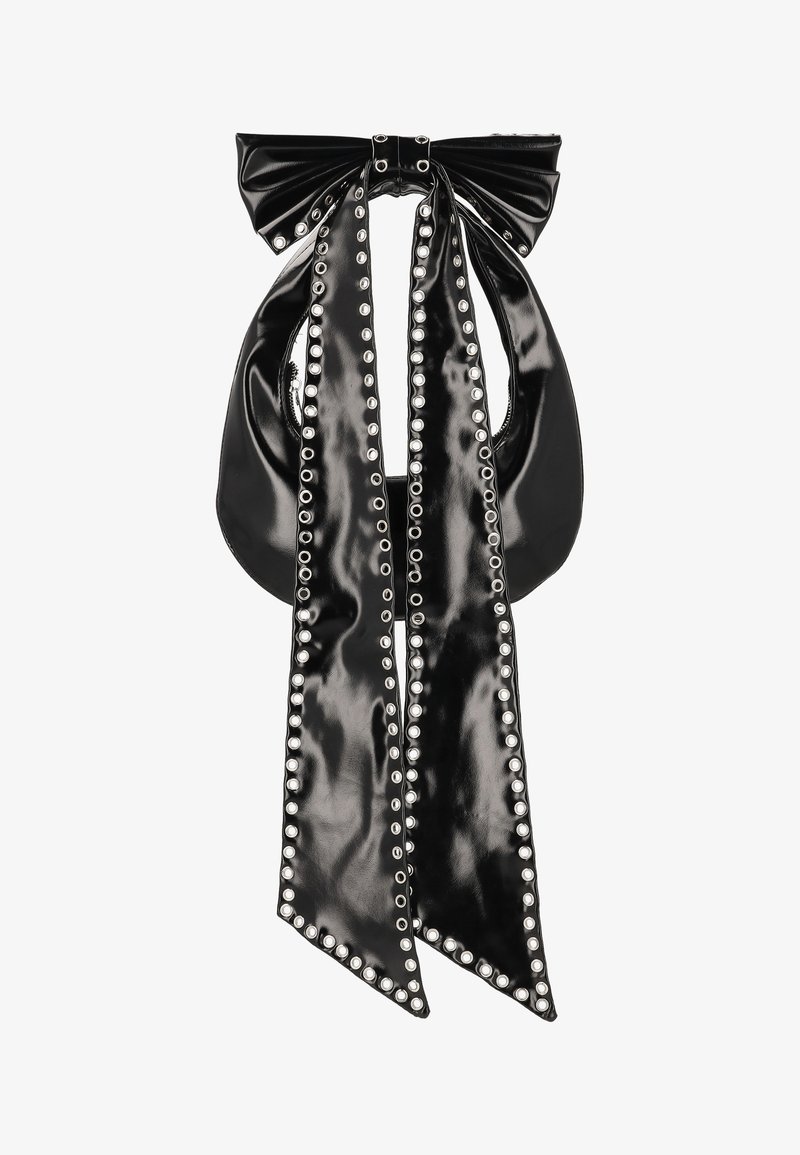 Černá kabelka z lakované kůže s velkou mašlí nahoře a dvěma dlouhými pásky připomínajícími stuhy. Okraje a otvory lemují stříbrné cvoky.