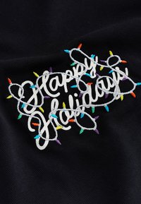 Tela negra con texto bordado "Felices Fiestas" rodeado de luces decorativas de colores en tonos azul, naranja, amarillo y morado.