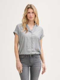 Gestreifte Kurzarmbluse in Grau und Weiß, mit Kragen und Knopfverschluss, kombiniert mit grauen Slim-Fit-Jeans. Glatte Textur.