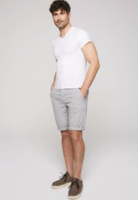 Witte katoen t-shirt, grijze katoen korte broek en bruine suede schoenen. De outfit heeft een casual pasvorm en minimale ontwerpelementen.