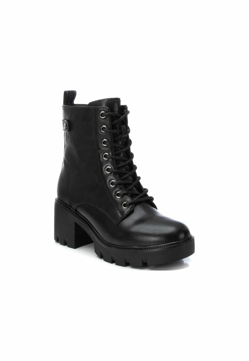 Schwarze Leder-Stiefelette mit einem klobigen, strukturierten Blockabsatz, Schnürverschluss vorne und metallischen Ösen. Schlaufe am Rücken für ein einfaches An- und Ausziehen.