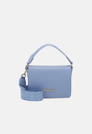 Kleine rechthoekige blauwe leren handtas met korte handgreep en afneembare patroonband, met goudkleurig merklogo aan de voorkant.