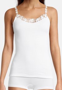 White camisole with lace trim along the neckline and straps. Soft, lightweight fabric with a seamless design. Ideal for layering.