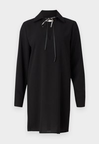 Robe noire à manches longues avec un col, présentant une découpe en forme de trou de serrure et un nœud avec des accents argentés sur le col. Texture lisse.