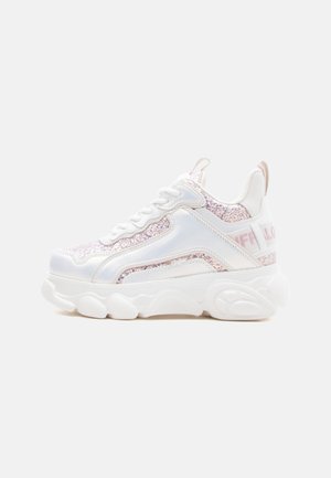 Pantof sport alb cu talpă groasă, panouri roz sclipitoare, șireturi în față și o buclă la călcâi, pe un fundal simplu și deschis.