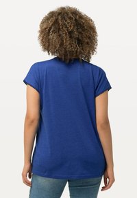 Camiseta azul de manga corta con un corte holgado y dobladillo festoneado en las mangas. Tejido suave y diseño de dobladillo curvado.