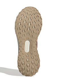 Suola in gomma con una superficie texturizzata e decorata, dotata di scanalature profonde per una migliore presa; colore beige con un accento bianco vicino al centro.