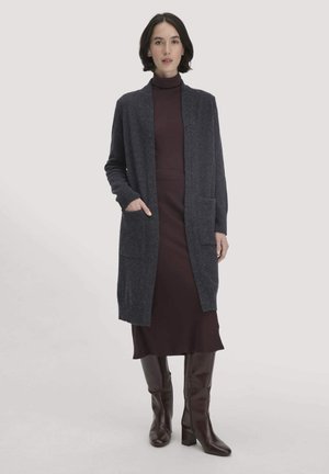 Langer, dunkelgrauer Cardigan aus weichem Material, mit offenem Vorderteil, langen Ärmeln und zwei Fronttaschen, getragen über einem dunklen Kleid und Stiefeln.