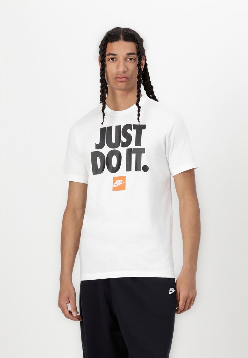 Balta medvilninė marškinėliai su dideliu juodu užrašu "JUST DO IT." ir oranžiniu Nike logotipu. Trumpomis rankovėmis ir apvaliu kaklu.