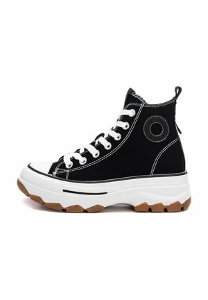 Zapatillas negras de caña alta con costuras blancas, diseño de cordones, punta de goma y una suela blanca gruesa con una banda de rodadura de goma marrón. Detalle de logo redondo.