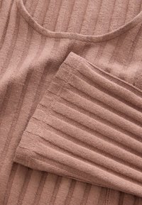 Ribbvävd tyg i en mjuk mauve-färg, med en rundad halsringning och ett strukturerat mönster med växlande ränder.