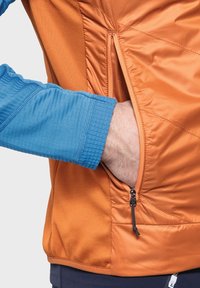 Orangenjacke mit einem blauen Ärmel, ausgestattet mit einer seitlichen Reißverschlusstasche und gestepptem Muster. Glattes Material mit einem kontrastierenden Farbdesign.