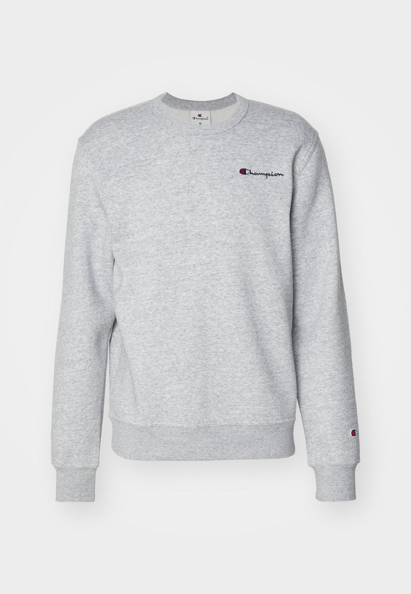 Sudadera gris hecha de tela suave, con puños y dobladillo acanalados. En la parte frontal tiene un pequeño logo bordado de "Champion" en azul y rojo.