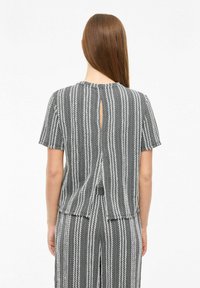Gray striped top with short sleeves, featuring a back keyhole cutout and a textured fabric. Vertical lines dominate the design.