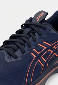 Marine løpesko med teksturert overdel, oransje detaljer og sorte lisser. Har et strømlinjeformet design og en polstret tunge for komfort.