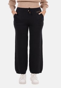 Pantaloni neri a gamba larga con vita elastica, chiusura con coulisse e tasche laterali; presenta un piccolo dettaglio del logo dorato.
