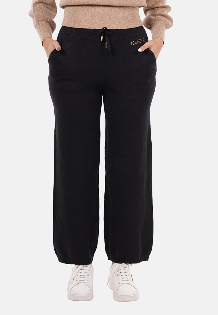 Pantaloni neri a gamba larga con vita elastica, chiusura con coulisse e tasche laterali; presenta un piccolo dettaglio del logo dorato.