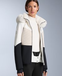 Jakna na napuhavanje s kapuljačom od bijelog umjetnog krzna, bež postavljenim prednjim dijelom i crnim rukavima. Ima patentni zatvarač, kopčanje na gumbi i moderan dizajn.