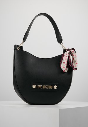 Sort måneformet håndtaske med en enkelt rem, guld "Love Moschino" logoplade og et hvidt og lyserødt mønstret tørklæde bundet til håndtaget.