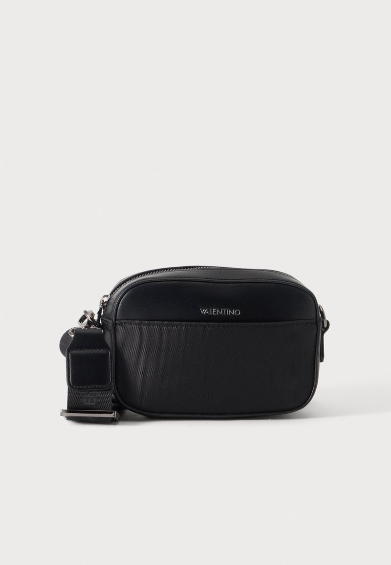 Μικρή μαύρη τσάντα Valentino crossbody με ασημί μεταλλικά στοιχεία, μπροστινή τσέπη, κλείσιμο με φερμουάρ και ρυθμιζόμενο λουράκι, εμφανίζεται σε απλό λευκό φόντο.
