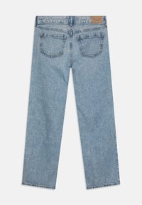 Jean en denim bleu clair avec une coupe droite, comportant deux poches arrière et une étiquette en cuir sur la taille.
