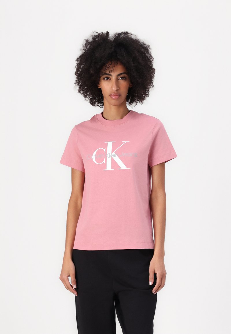 Rosa bomull t-skjorte med kort erm, rund hals, og en stor hvit logo med teksten "Calvin Klein Jeans".