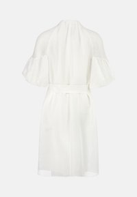 Weißes Leinenkleid mit hohem Kragen, kurzen schwingenden Ärmeln und einem Taillengürtel. Es hat ein fließendes Design und einen subtilen Glanz.