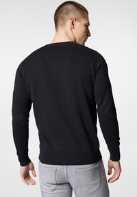 Czarny sweter dzianinowy z okrągłym dekoltem oraz prążkowanymi mankietami i dołem. Tył ma gładką teksturę i prosty design.