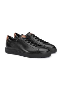 Sneakers basse in pelle nera con lacci neri e dettagli marroni sul tallone e sulla linguetta, posizionate fianco a fianco su sfondo bianco.